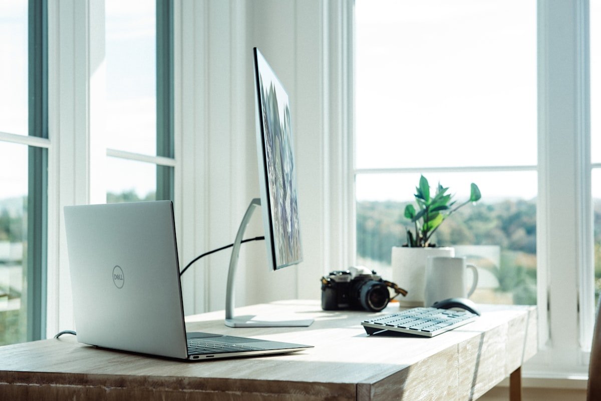 A clean well-positioned desk against a solid wall with clear view of the door, showing proper feng shui desk placement with command position and open workspace